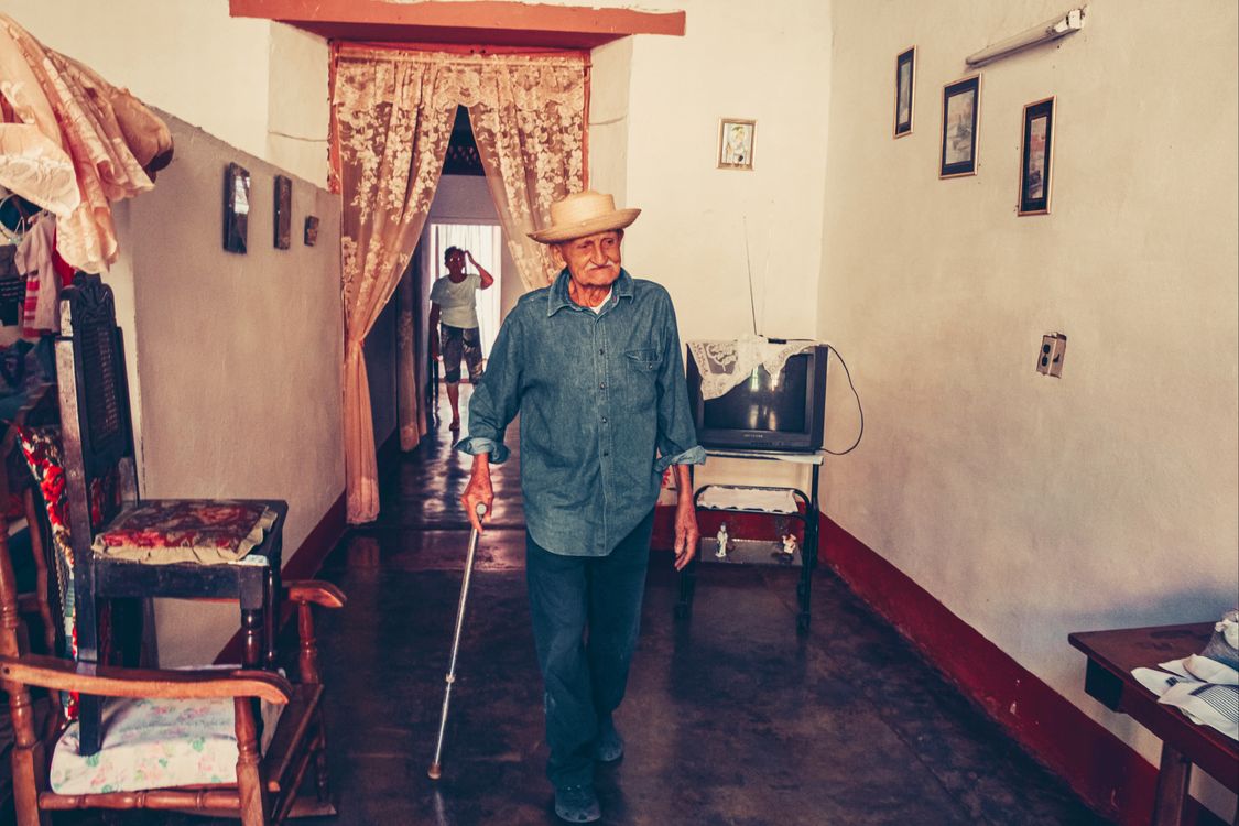 Older adult walking with a cane inside a furnished home